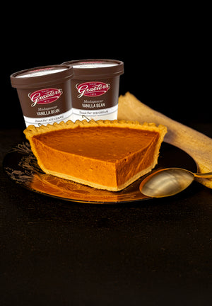 Servatii's Pumpkin pie slice with two containers of vanilla bean ice cream on a dark background